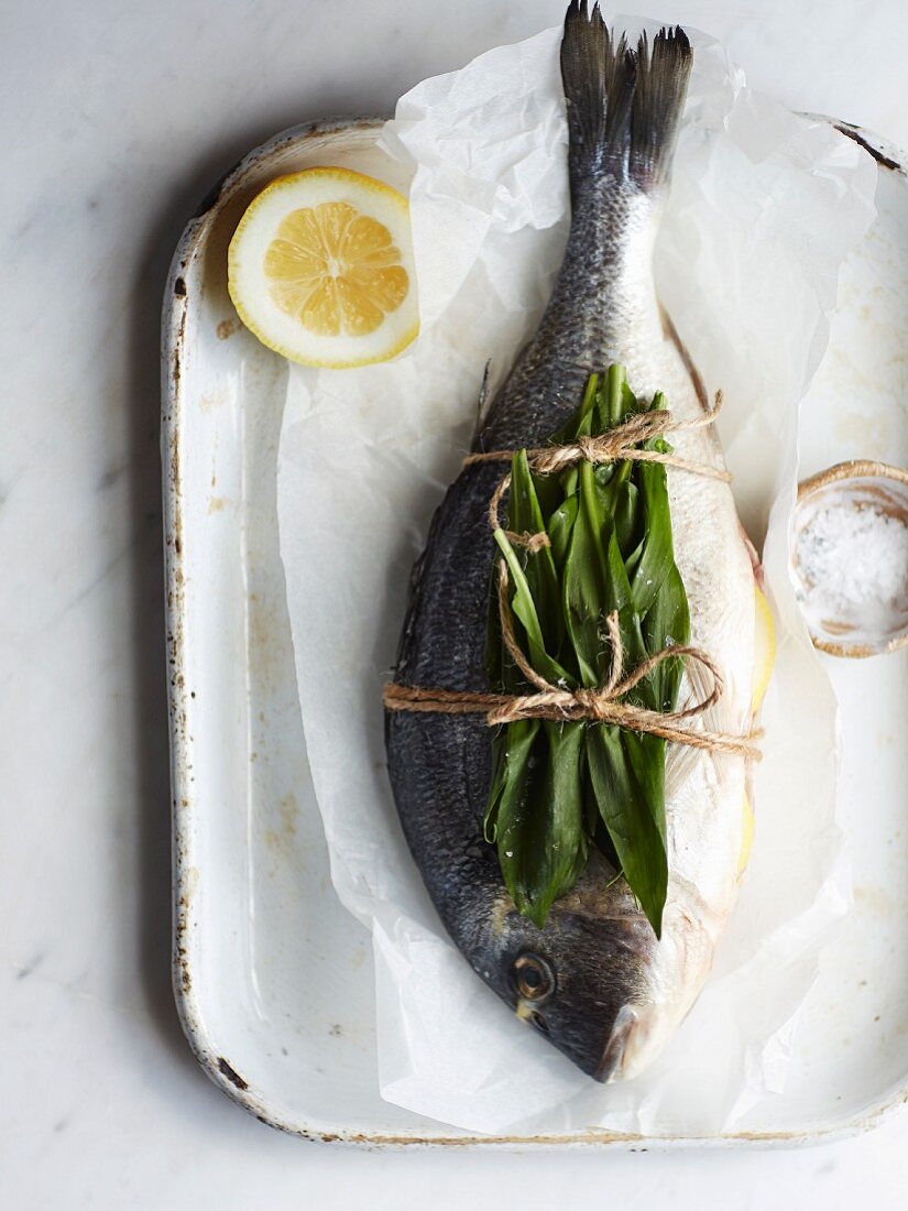 A whole sea bream with wild garlic on baking paper