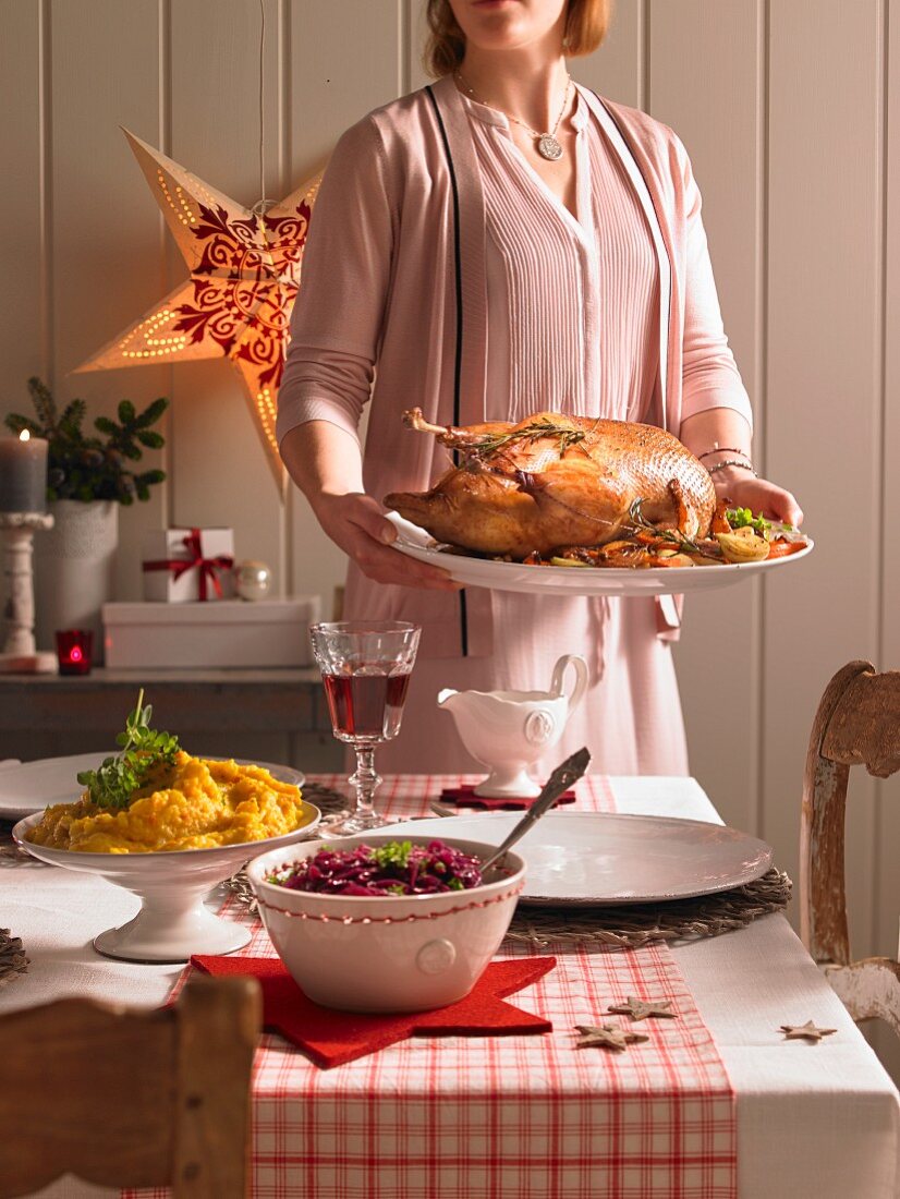 A woman serving a roast goose (Christmas)