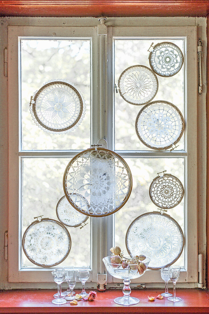 Lace doilies mounted in embroidery frames decorating window
