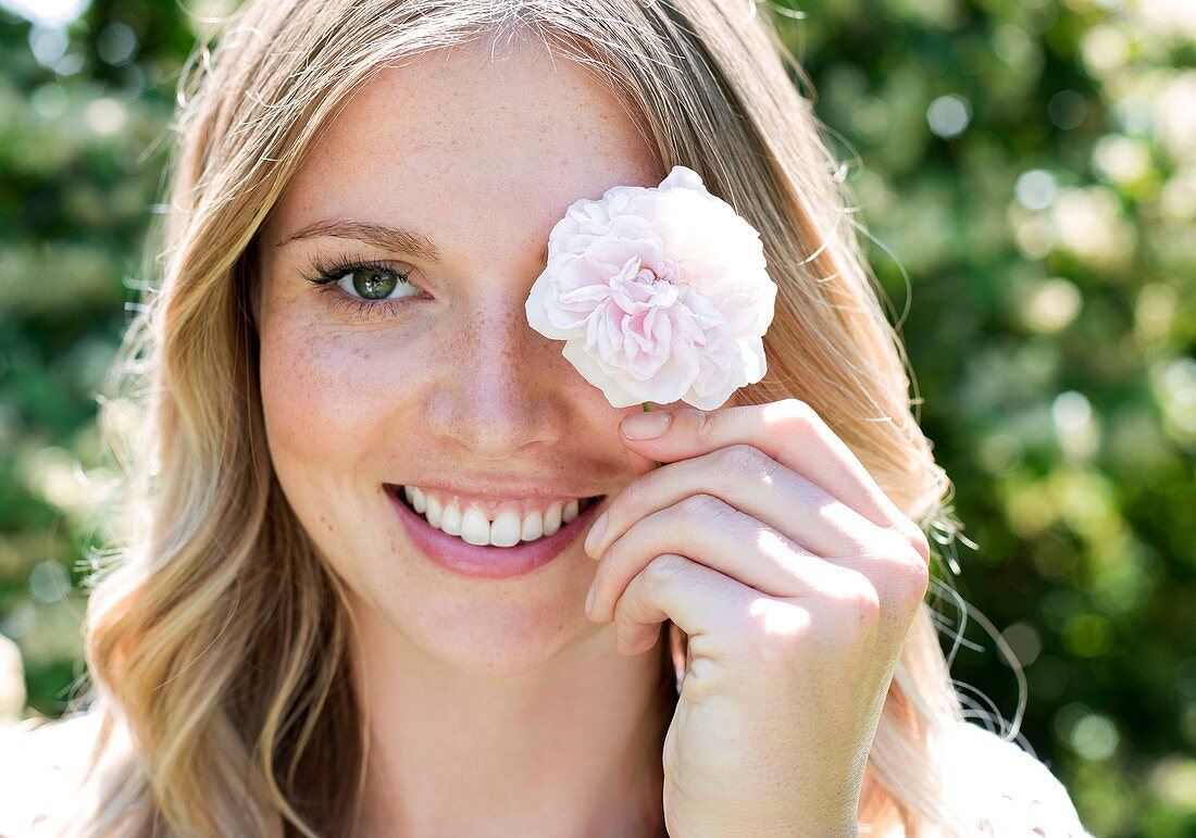 Woman holding flower in front of eye