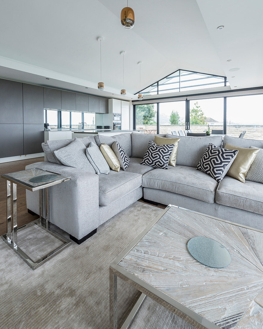 Graues Sofa mit gemusterten Kissen im großen offenen Wohnraum