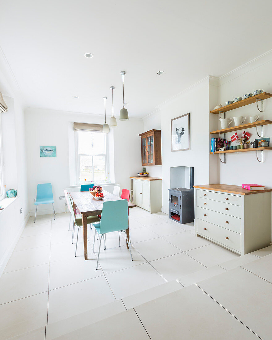 Steps leading down to dining room with colourful chairs around wooden table