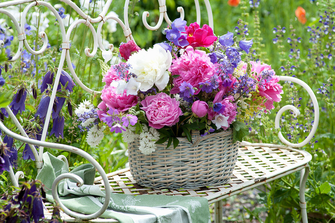 Basket with early-summer perennials arrangement on garden bench