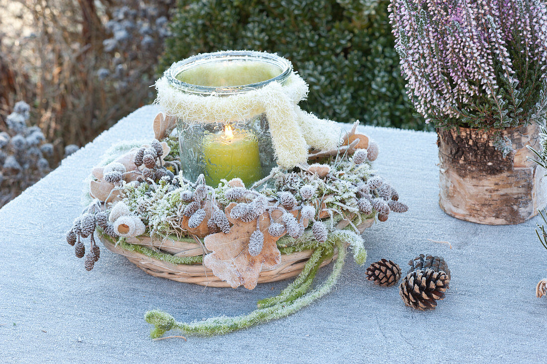 Frozen lantern with scarf in wreath of moss, branches, leaves