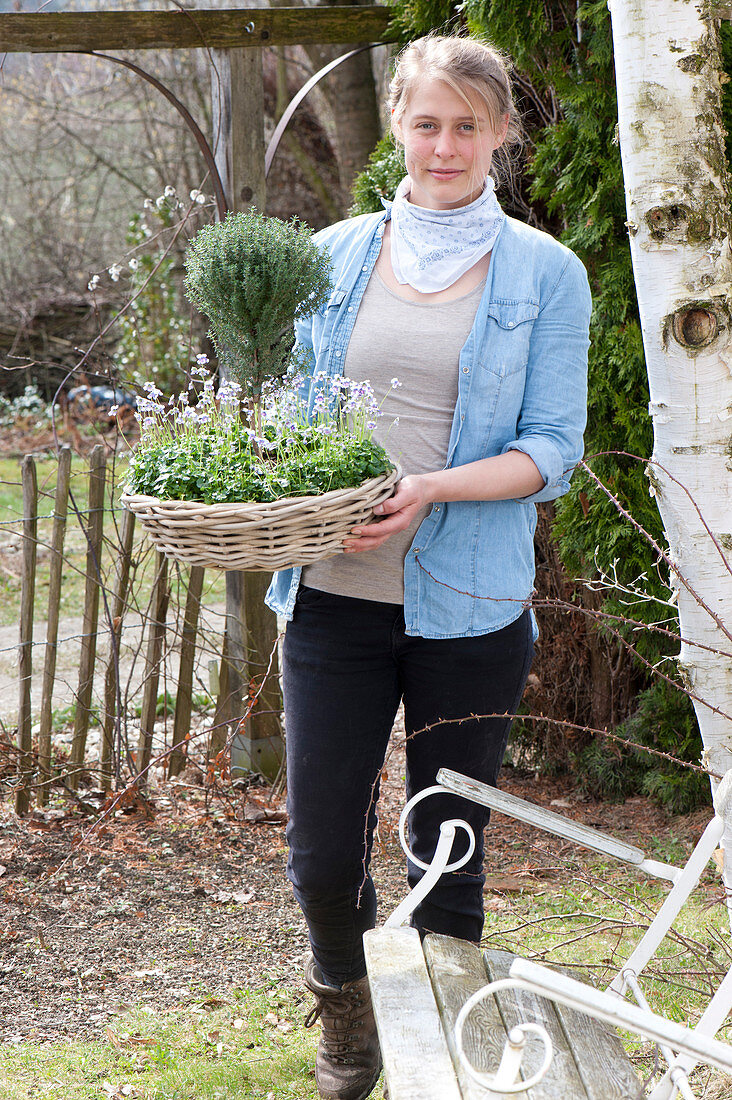 Woman bringing basket bowl with Thymus vulgaris as stem