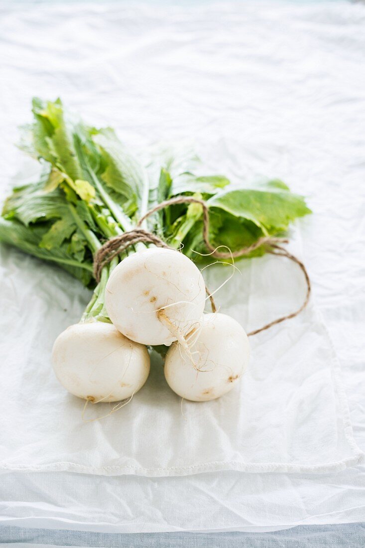 A bundle of white turnips on a pale background