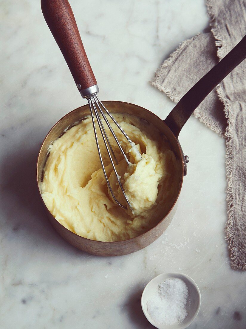 Mashed potatoes with a whisk in a saucepan