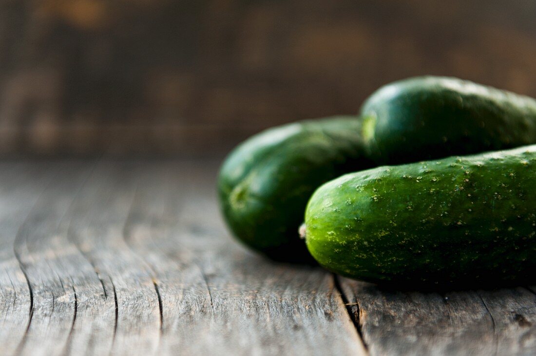 Three cucumbers on a wooden background