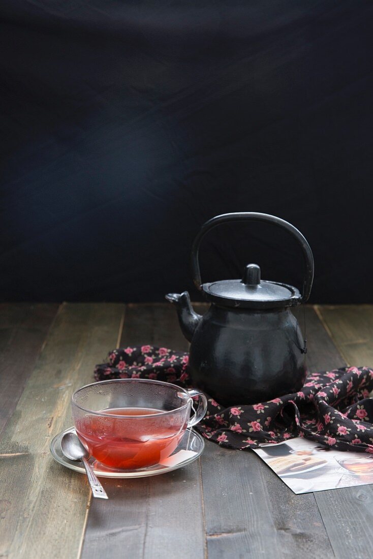 Stillleben mit Teekanne und Kräutertee in Glastasse