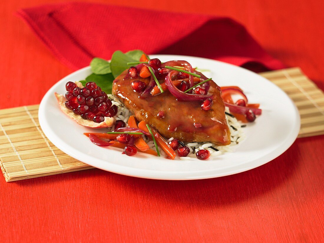 A chicken breast with pomegranate sauce on wild rice