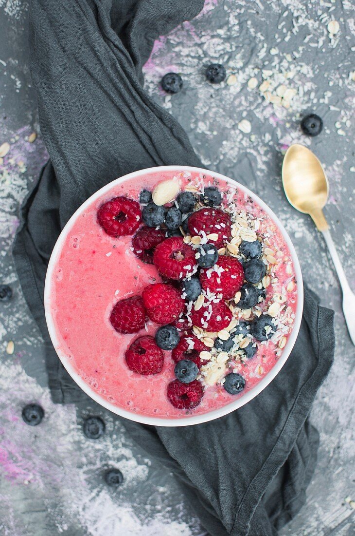 A strawberry smoothie bowl with yoghurt, raspberries, blueberries and coconut flakes