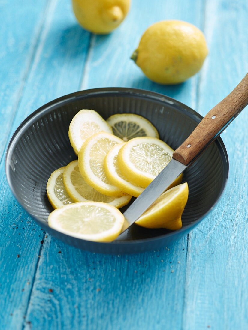 Lemon slices with a kitchen knife in a small bowl