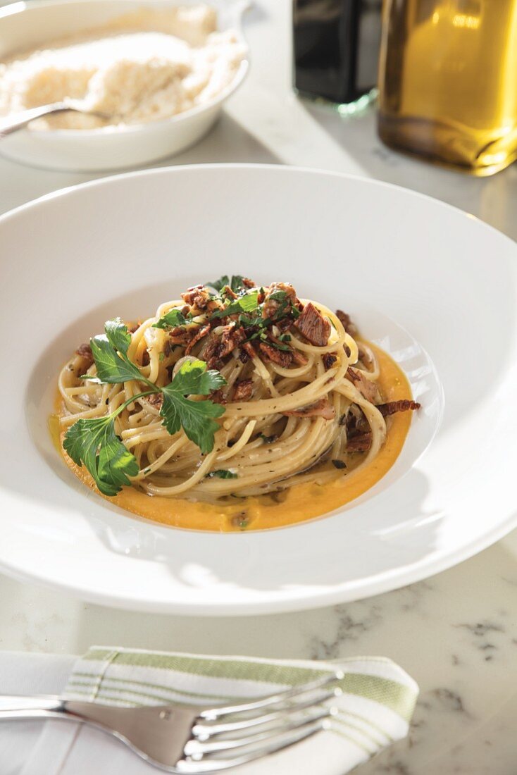 Spaghetti with Chanterelles and Black Truffle over Butternut Squash Purée in white wide-rimmed bowl