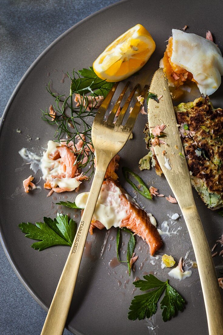 Zucchini-Fritters mit Lachs und pochiertem Ei: Essensreste auf Teller