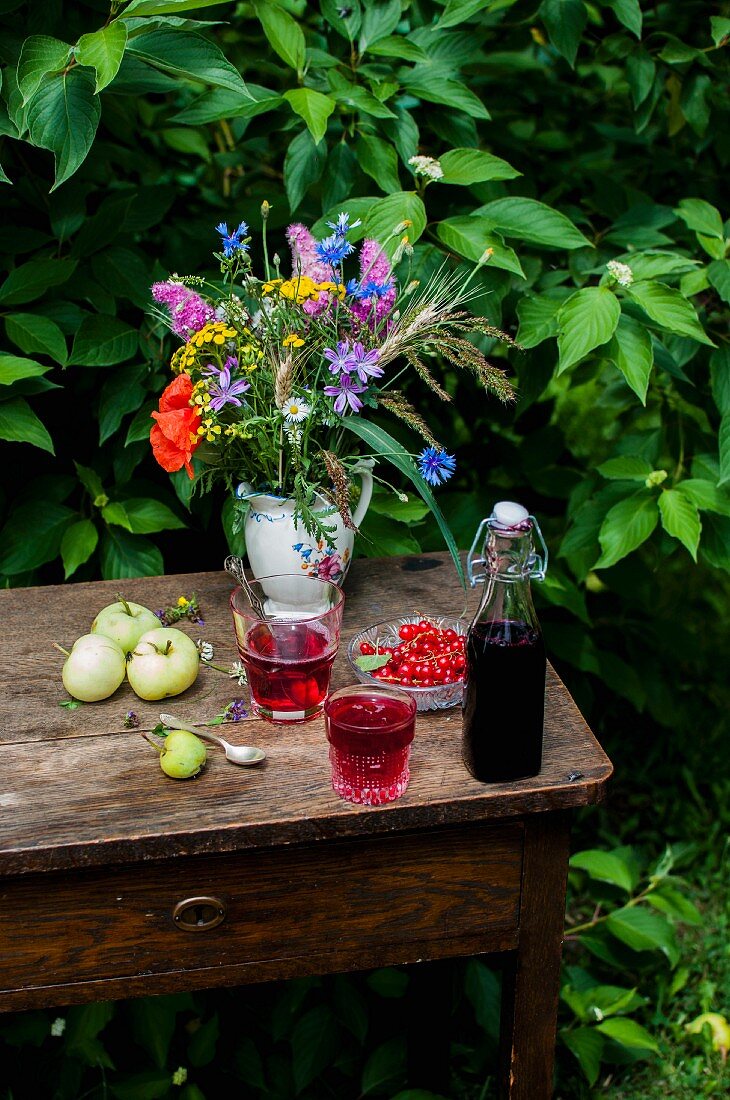 Currant syrup and currant lemonade on a summer table in a garden