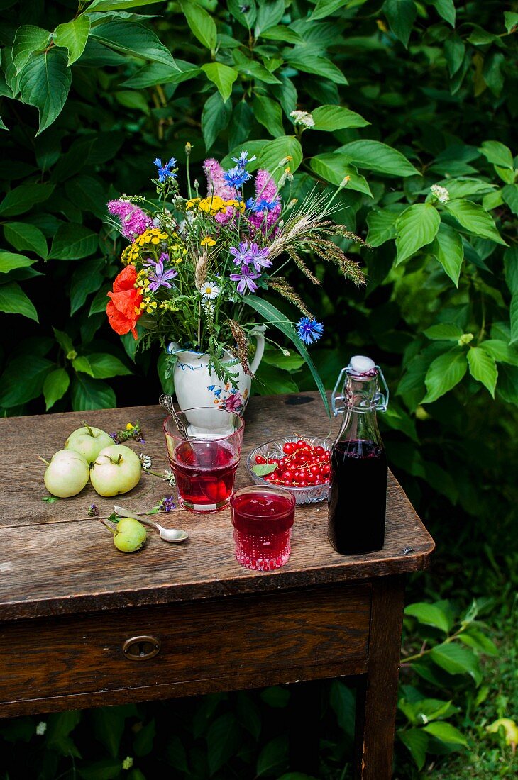 Johannisbeersirup und Johannisbeerlimonade auf sommerlichem Tisch im Garten