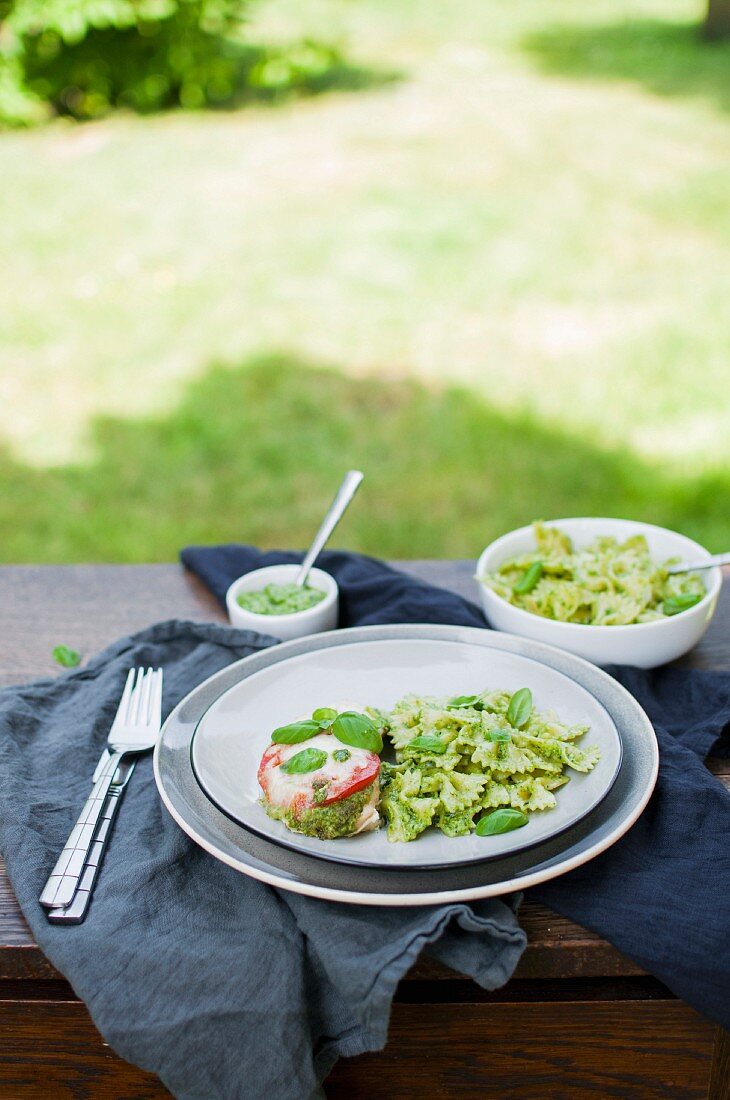 Baked chicken breast with pesto pasta on a table in a garden