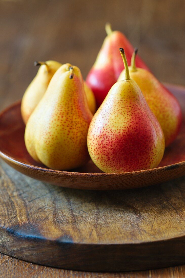 Yellow and red pears on a wooden plate
