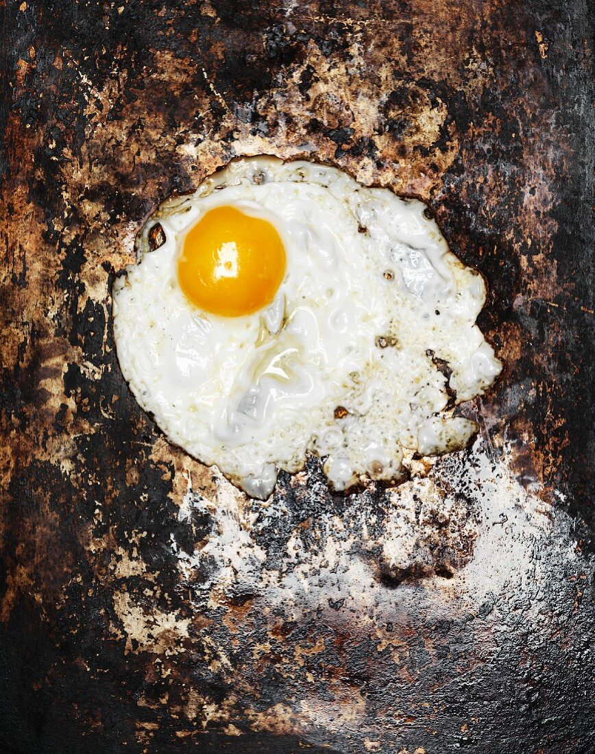 A fried egg on a rusty metal plate (top view)