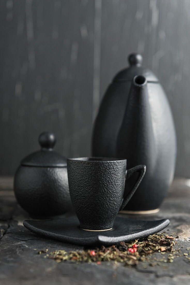 Tee in schwarzer Schale vor Teekanne und Zuckerdose