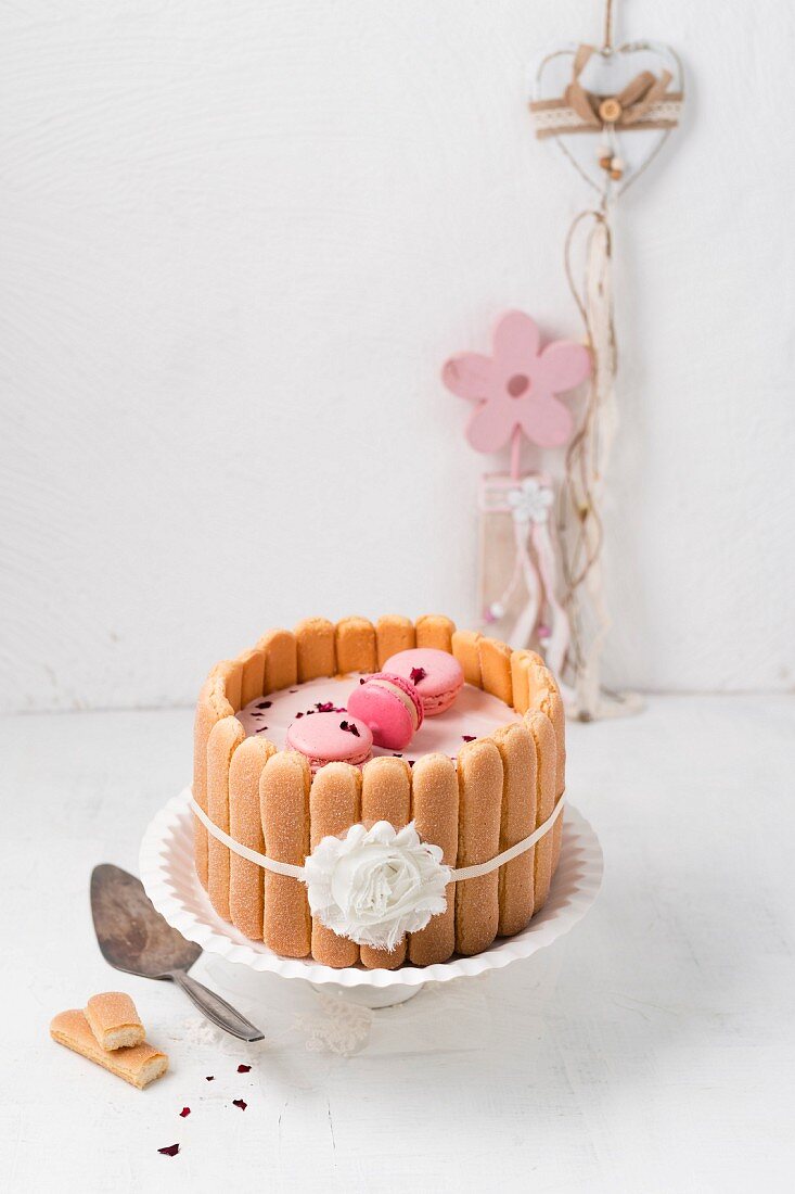 A raspberry cream cake with raspberry macarons, sponge biscuits and rose petals