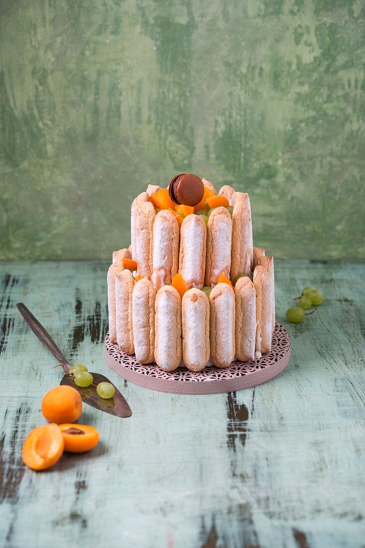 A cake with sponge biscuits, fruit and macarons