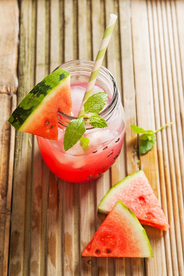 Wassermelonensaft im Glas mit Eiswürfeln, Minze und Wassermelonenstück