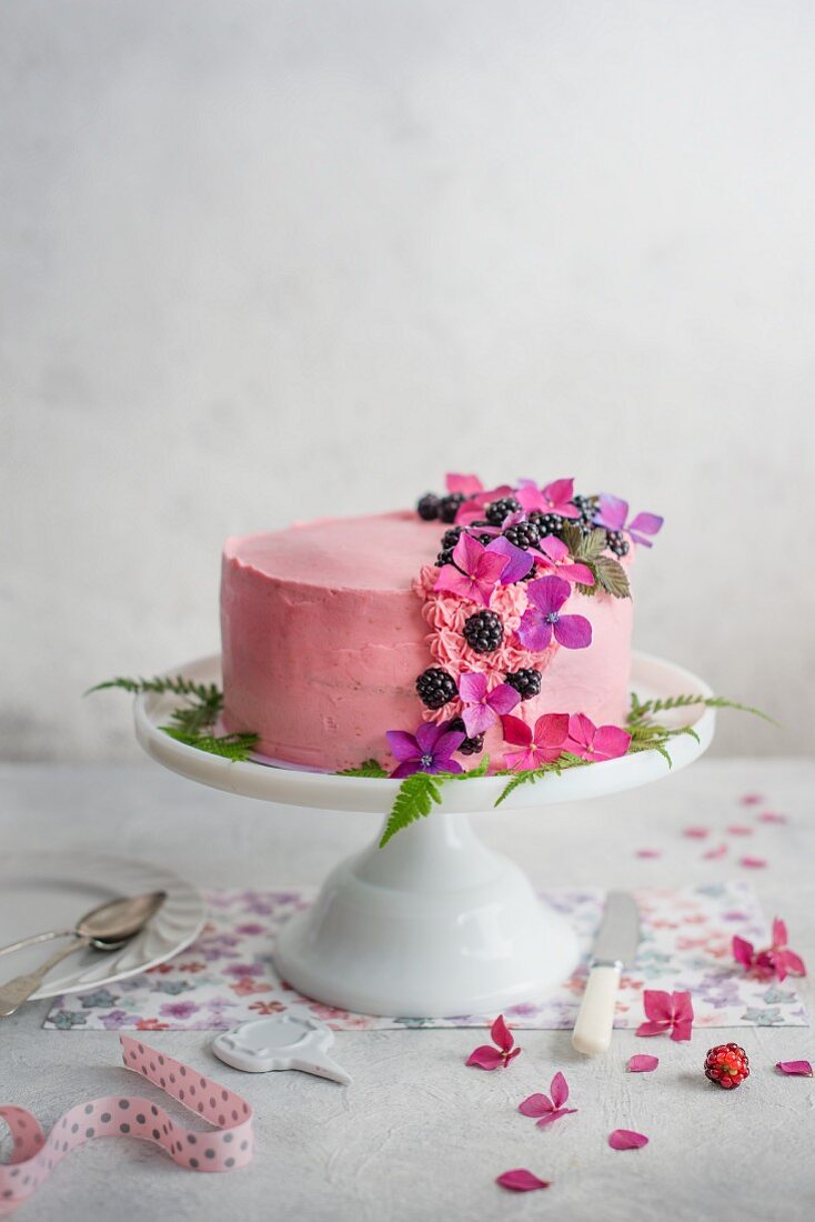 Festive blackberry sponge cake with blackberry cream on a cake stand