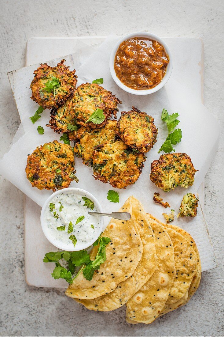 Spicy courgette fritters with mint, cucumber raita, apricot chutney, flatbread and coriander leaves