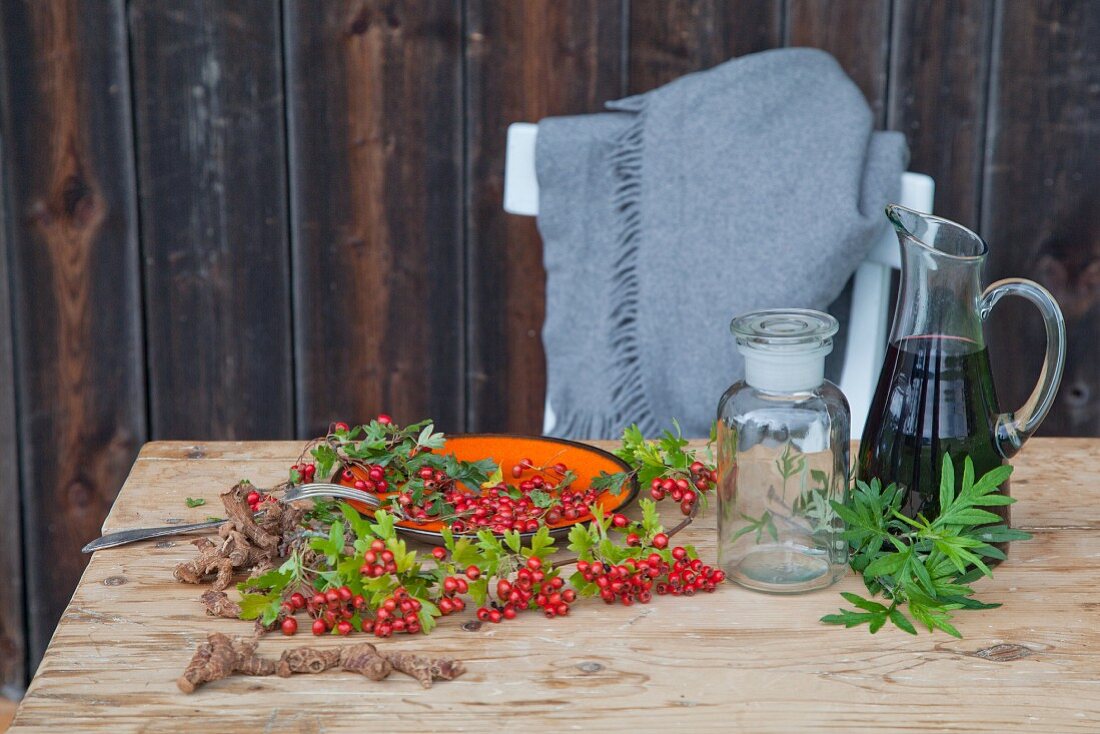 Red wine and hawthorn berries on a wooden table (ingredients for making wine)