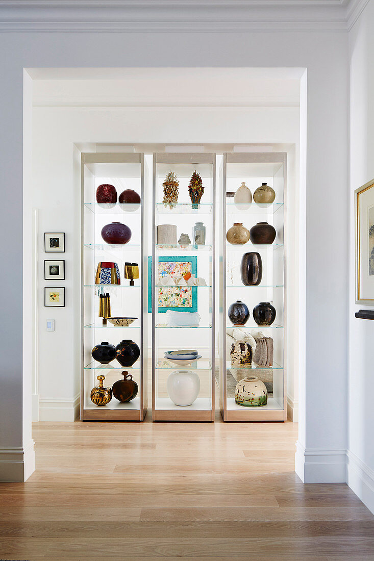 Three modern glass showcases with vases in a niche