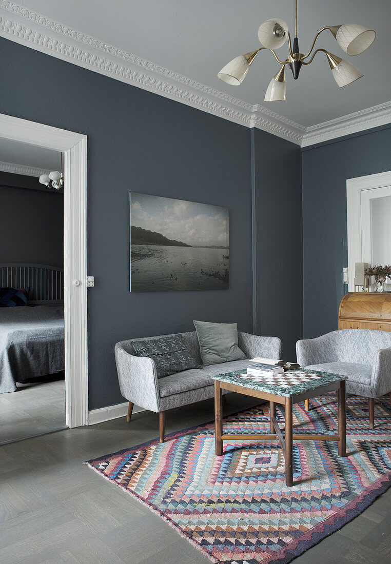 Sofa and armchair around chess table in room with grey walls