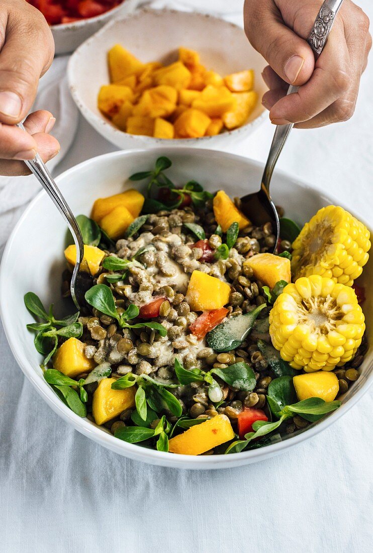 A bowl of lentil salad with sweetcorn, peaches and lamb's lettuce
