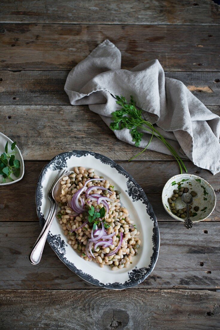 Bohnensalat mit weissen Bohnen und Zwiebeln auf rustikalem Holztisch