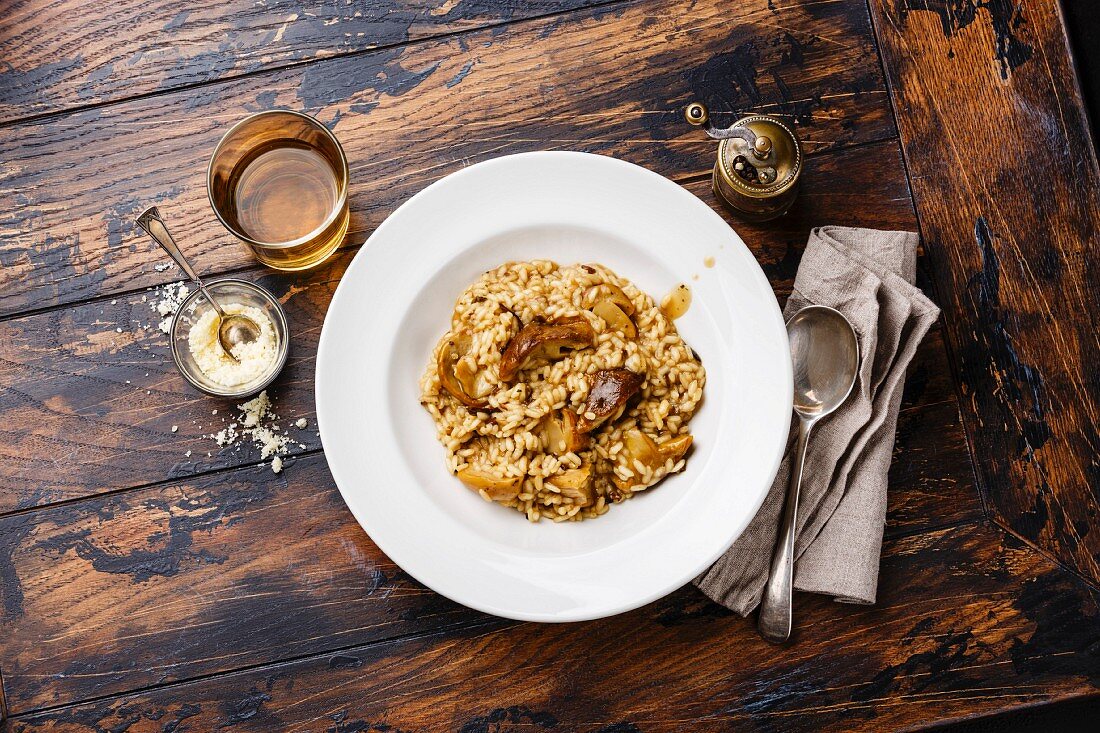 Risotto with porcini mushroom on plate on wood table background