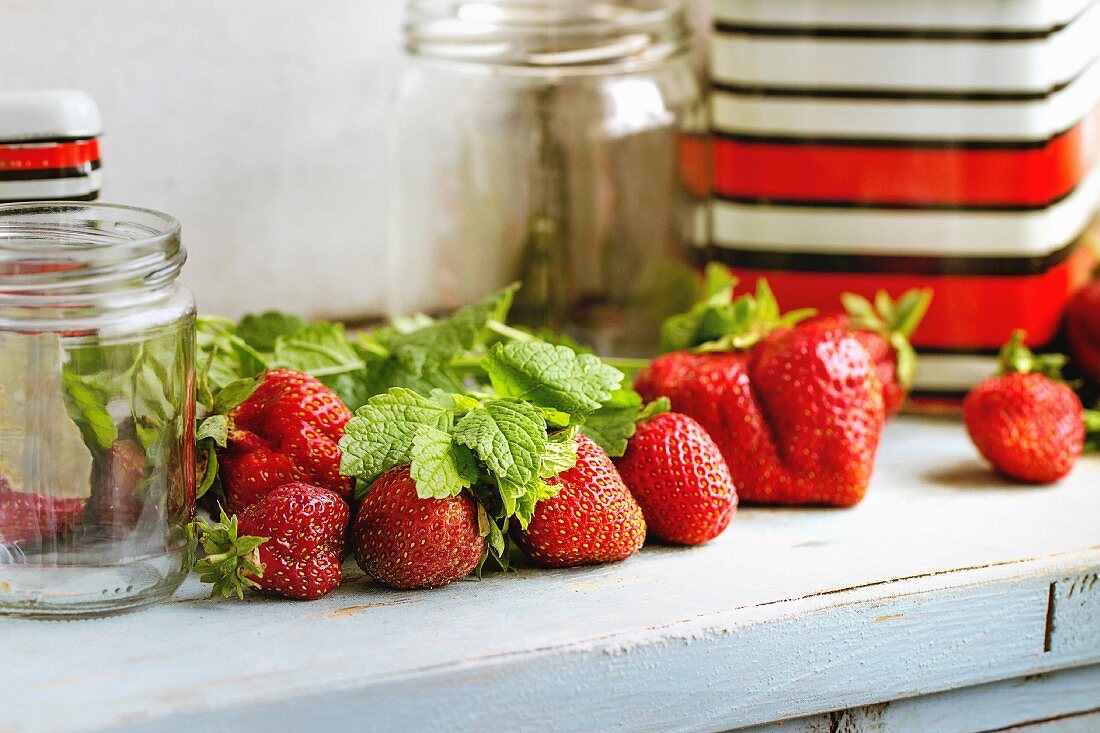 Stillleben mit frischen Erdbeeren, Melisse und leeren Einmachgläsern