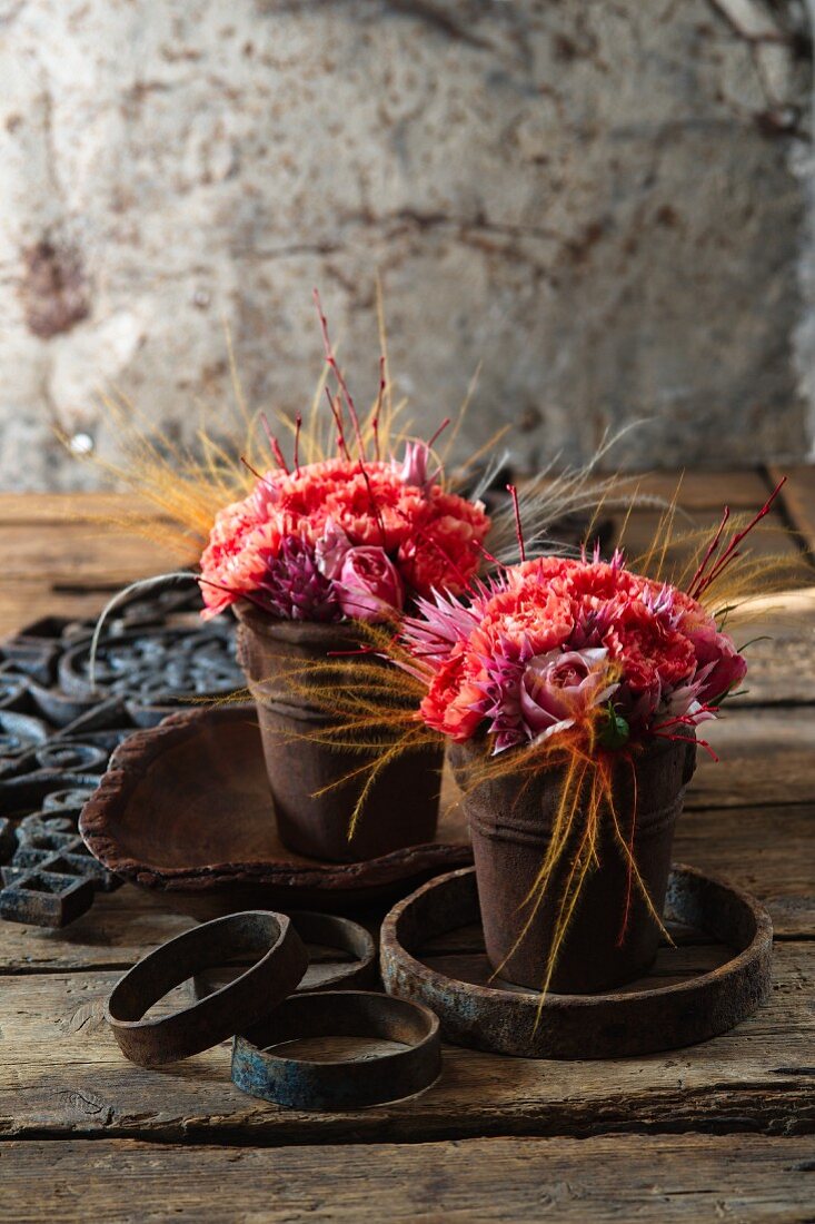 Small posy of roses and pinks in two rusty metal pots