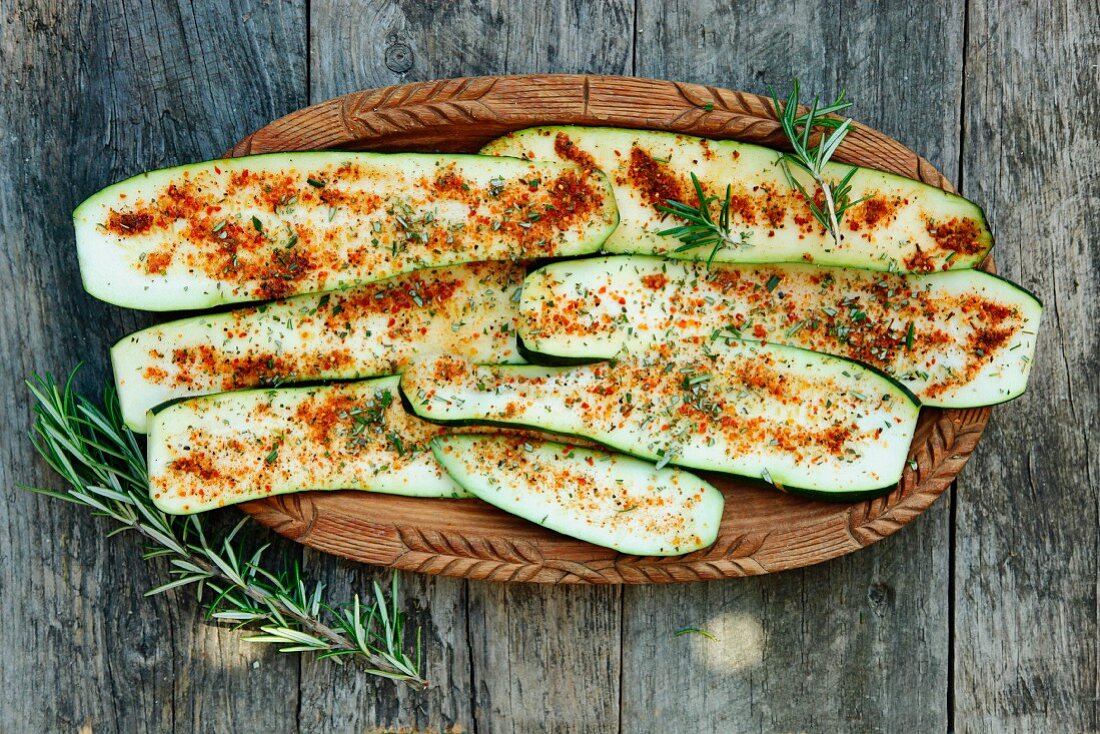 Courgette slices with paprika in a wooden bowl