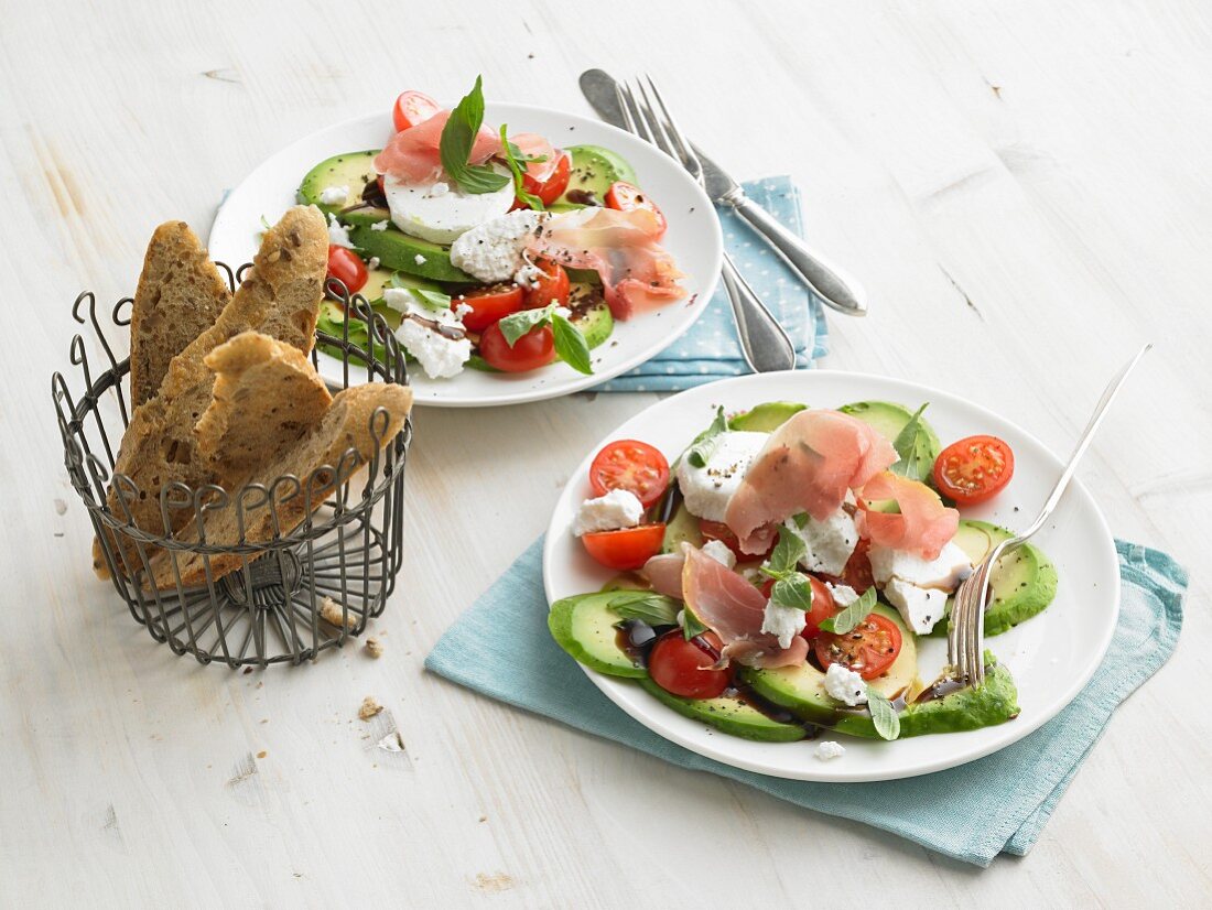 Avocado mit Ziegenfrischkäse, Rohschinken, Kirschtomaten und Vollkornbaguette