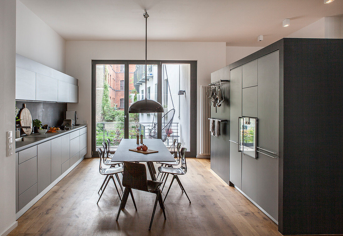 Modern dining set in large, grey fitted kitchen with balcony