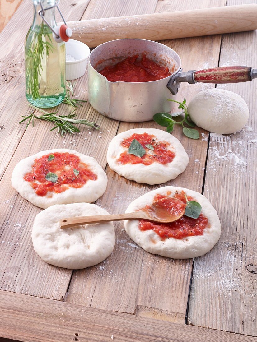Ungebackene Pizzaböden mit Tomatensauce bestrichen
