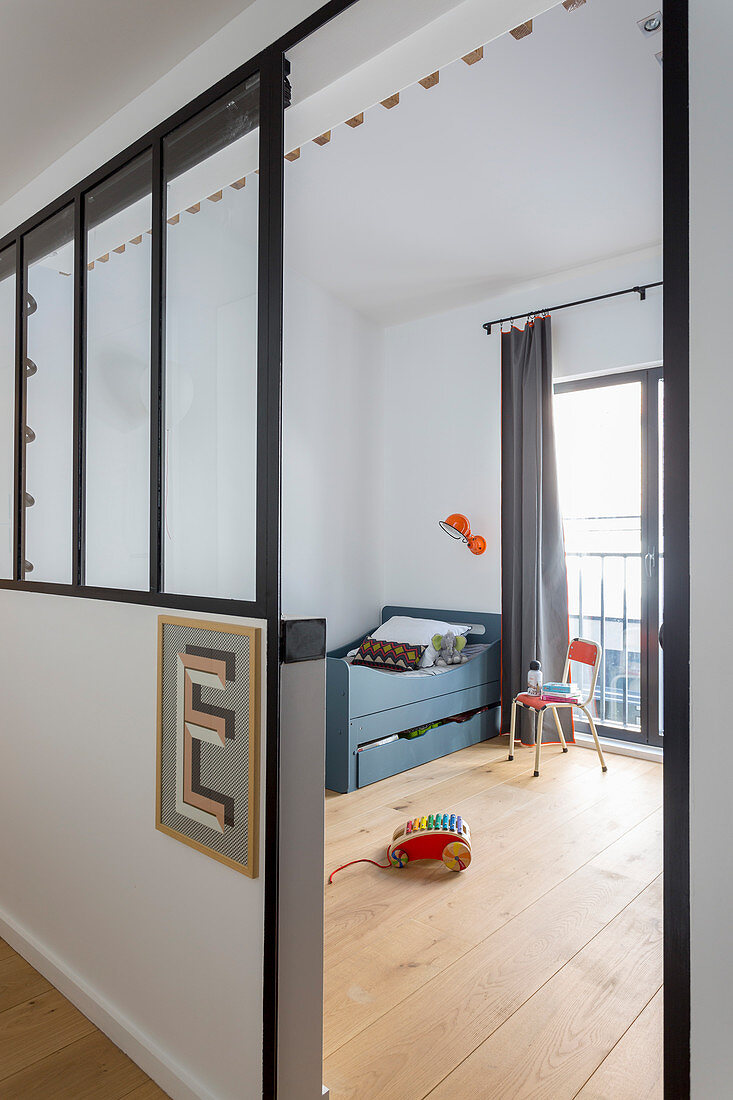 Letter E on half-height partition wall with interior windows screening child's bedroom