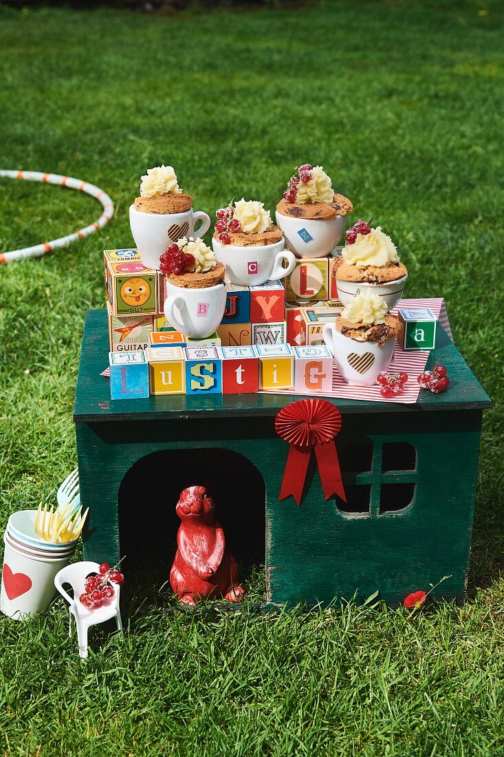 Chocolate cupcakes in teacups on a pet house for a children's party in the garden