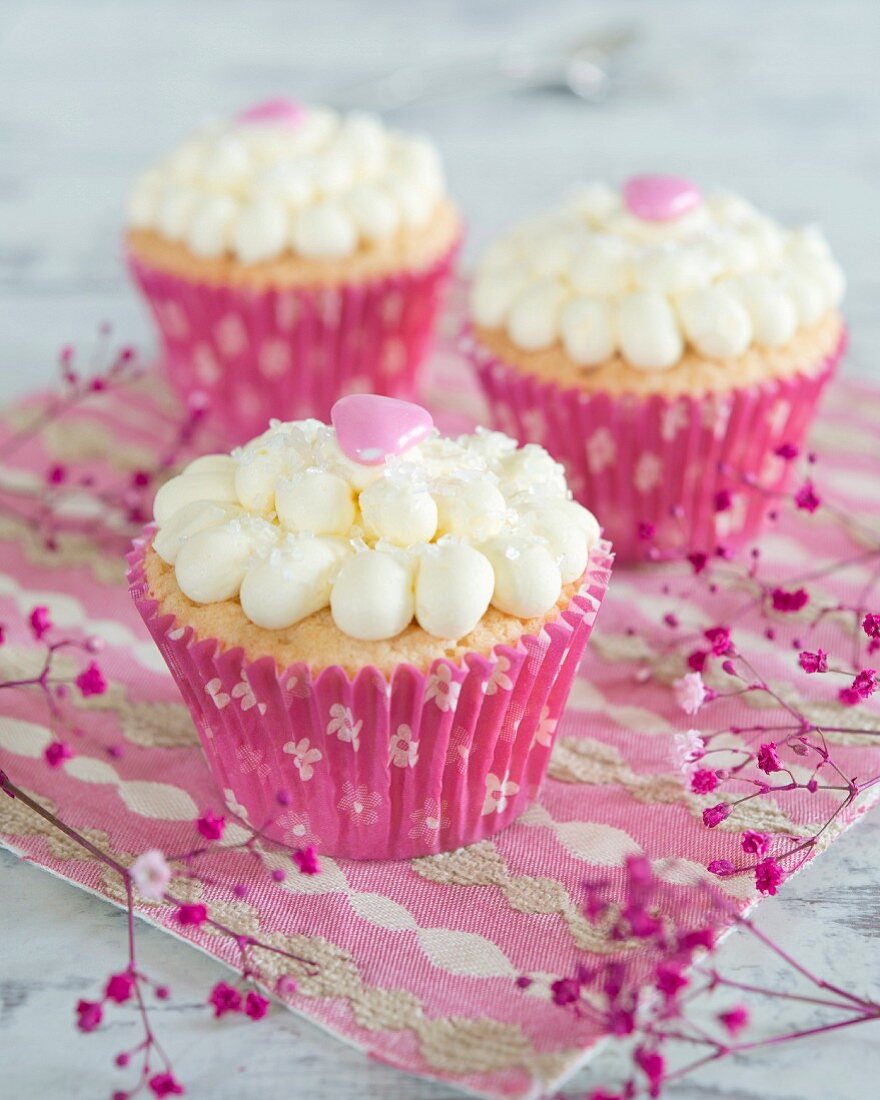 Cupcakes mit Cremetupfen und rosa Herzen