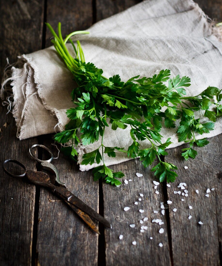 Fresh parsley, salt and scissors on a wooden background