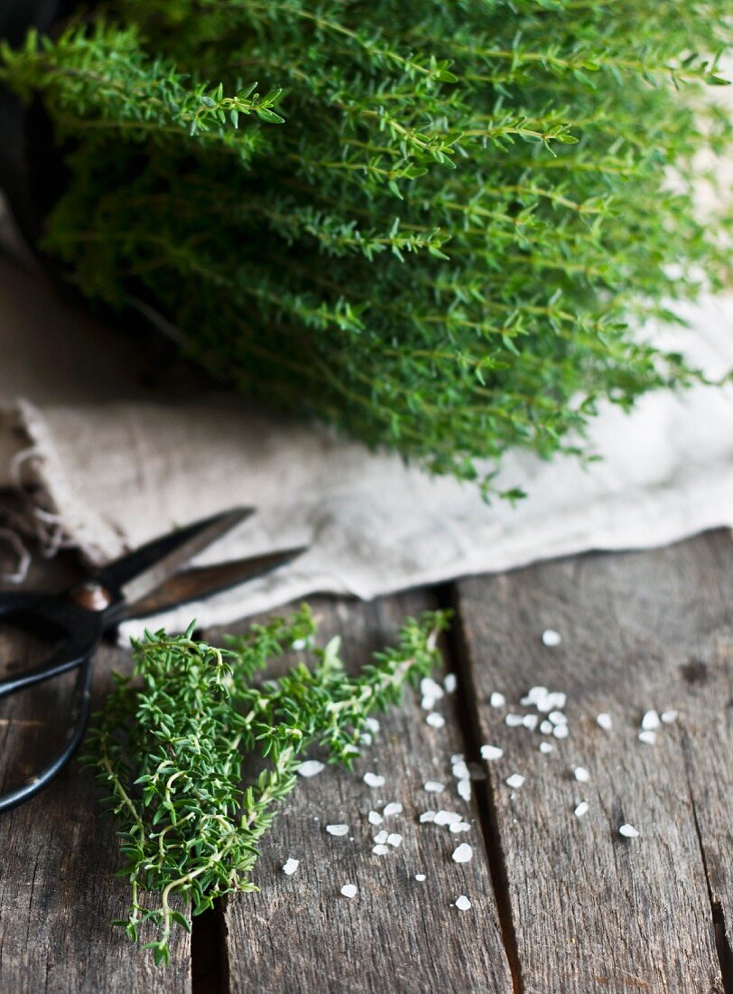 Fresh thyme and salt on a wooden background