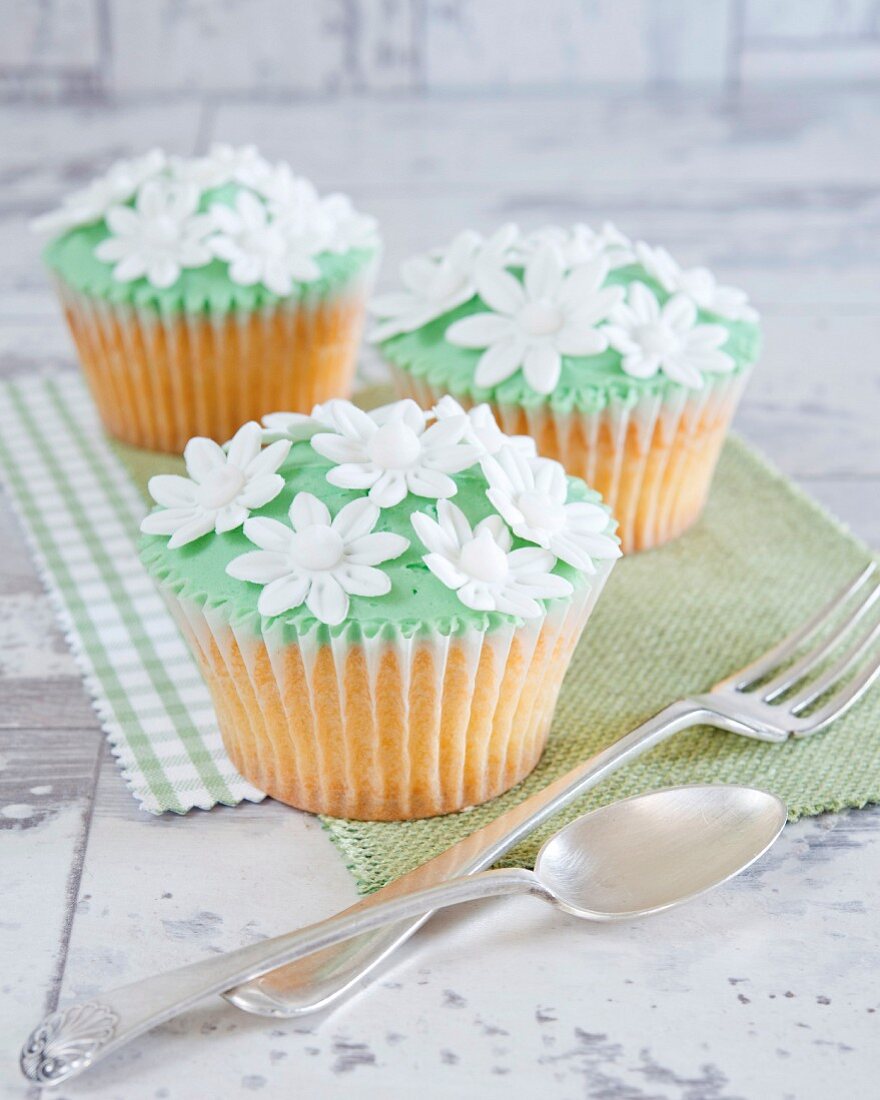 Cupcakes mit grüner Creme und weissen Zuckerblumen