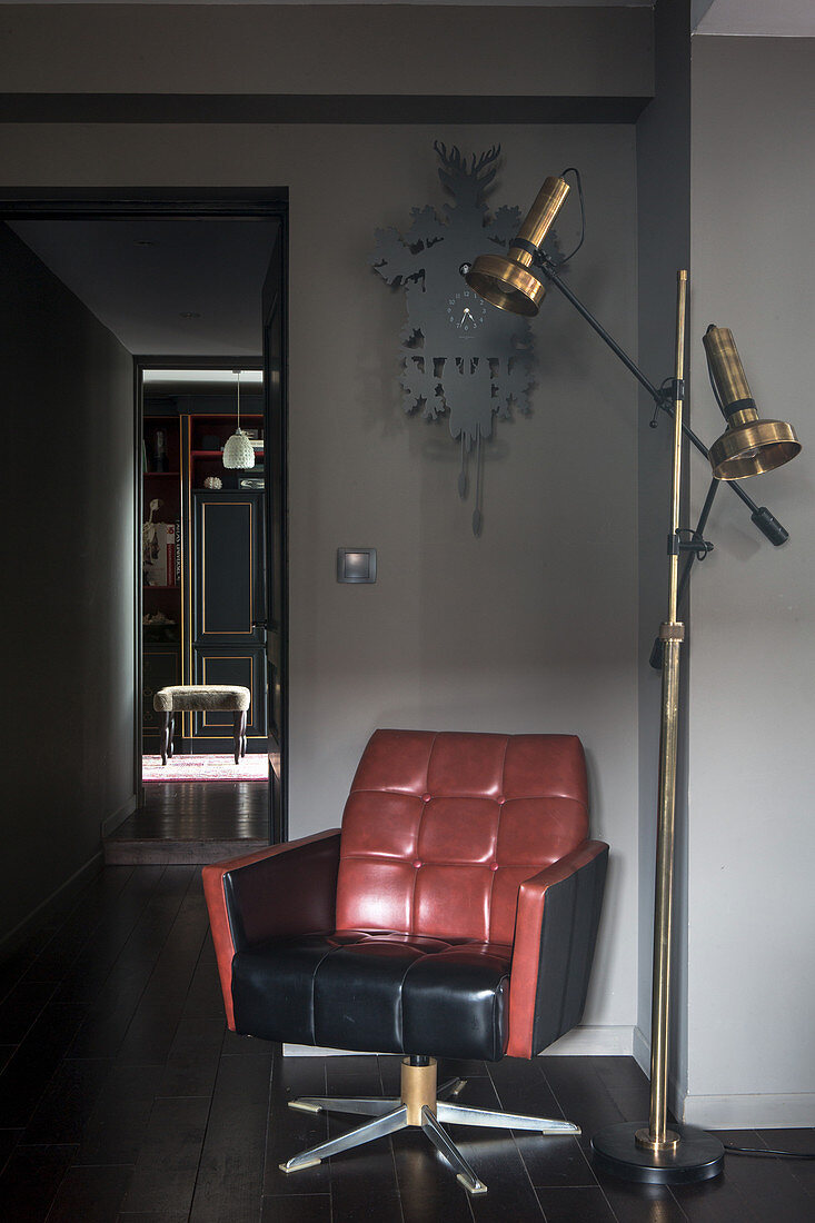 Retro-style leather armchair next to gilt standard lamp in hallway