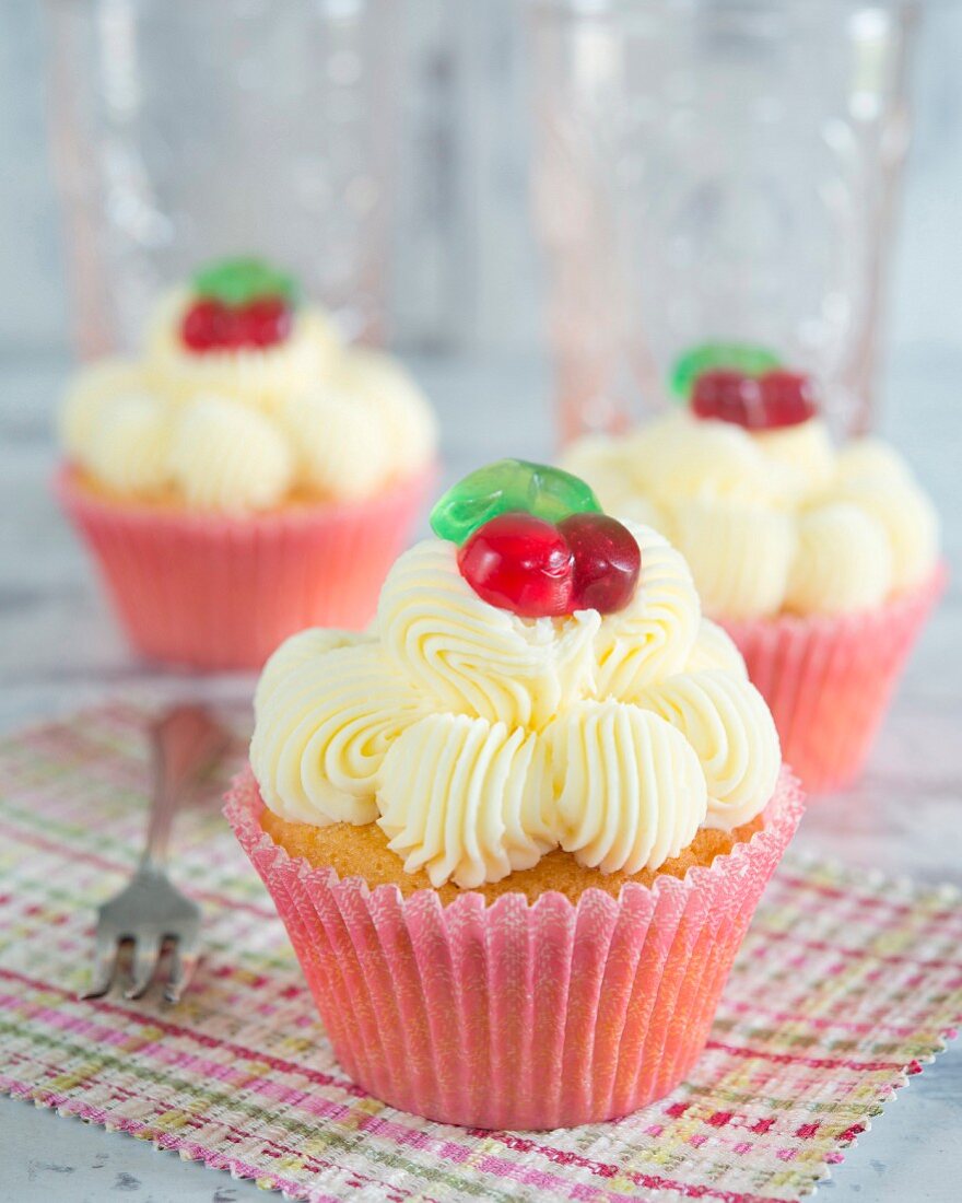 Cupcakes with butter cream and glace cherries