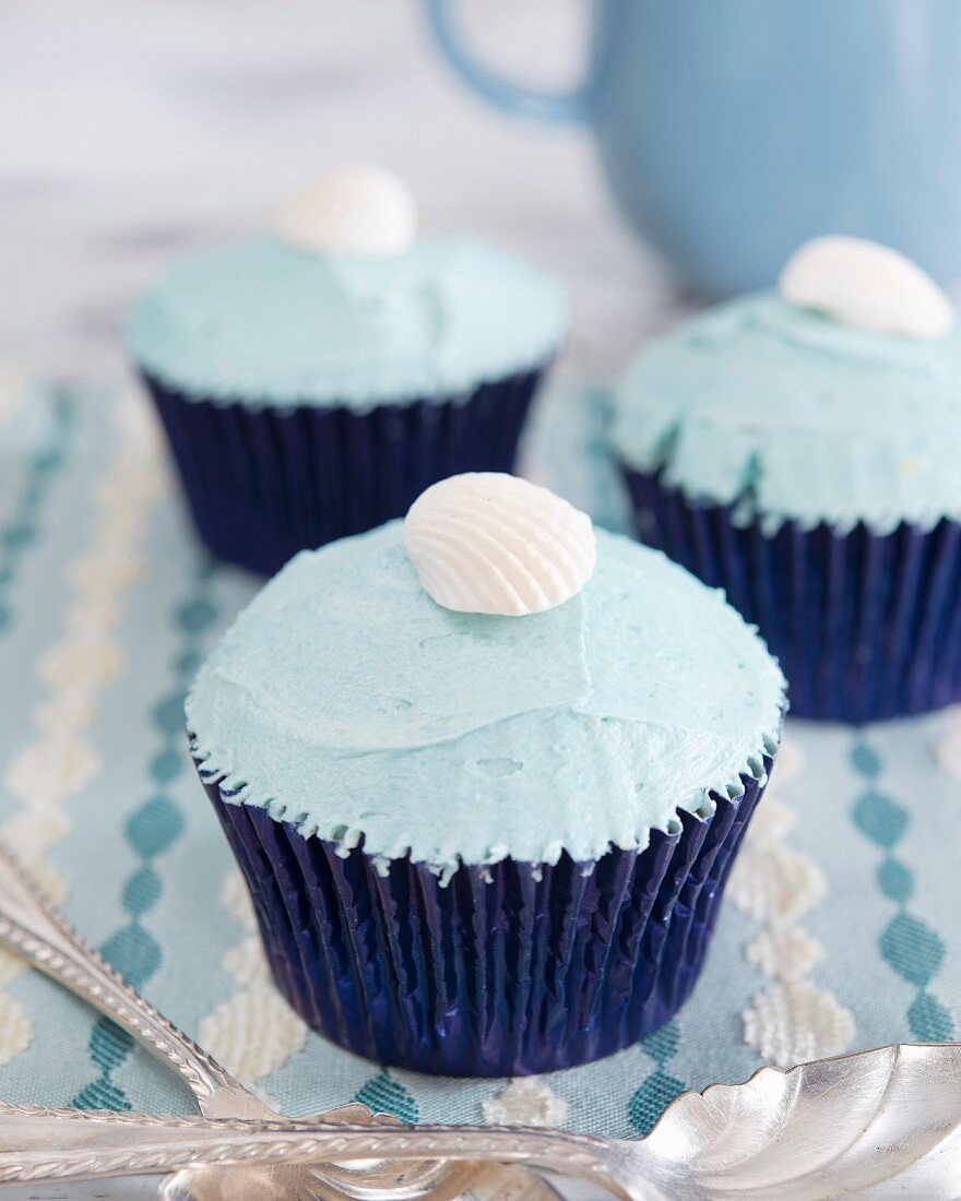 Cupcakes with blue cream frosting and a fondant shell on the top